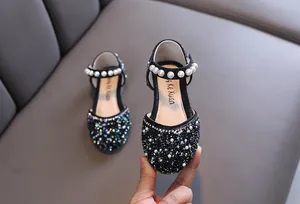 Gros plan de chaussures de princesse noires pour filles avec strass et bride en perles