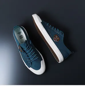 Détail de baskets en toile bleu marine pour hommes avec broderie tigre et semelles blanches.