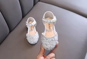 Gros plan de chaussures de princesse argentées pour filles avec strass et perles.