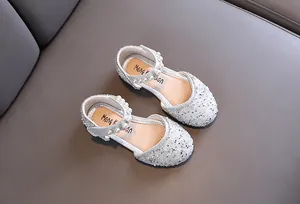 Détail de chaussures de princesse argentées brillantes pour filles avec brides en perles chic