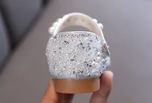 Gros plan montrant des strass scintillants et des perles élégantes sur le talon d'une chaussure de fille.