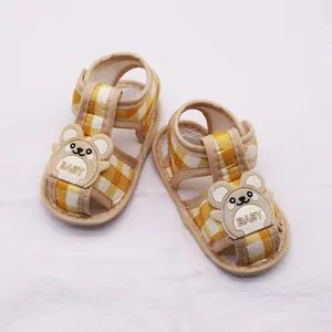 Vista superior de sandalias amarillas de cuadros para bebé con diseño de oso