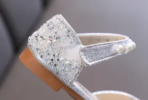 Gros plan détaillé des strass brillants et perles élégantes sur la chaussure de danse argentée.