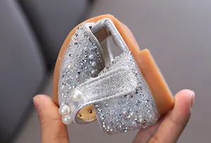 Vue rapprochée de chaussures de princesse argentées avec strass et perles brillants