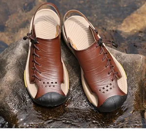 Macro detail of men's brown leather outdoor sandals resting on a wet river rock.