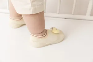 Close-up of baby floor sock shoes with a cute yellow bee plush ornament and soft sole