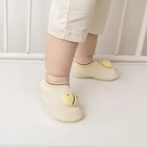 Close-up of baby wearing cream floor sock shoes with yellow bee decoration