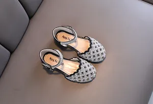 Detailed macro view of girls' black hollow-out dress shoes with sparkling rhinestones