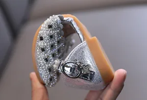 Macro detail showing the extreme flexibility of silver girls' princess shoes with pearls