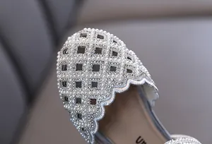 Close-up of girl's princess shoes featuring intricate hollow-out design with pearls