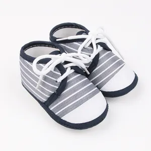 Detailopname van blauw gestreepte babyloopschoentjes met witte veters en neuskap.