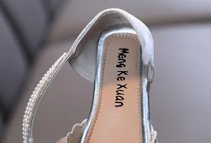 Close-up of silver girls' princess shoes with pearl strap and scalloped edge detail