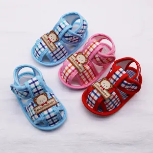 Close-up of baby plaid sandals in blue, pink, and red with cute cartoon bear patches.