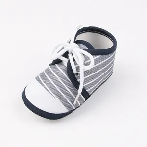 Detail van een marineblauw en wit gestreepte babyloopschoen met zachte zool en veters