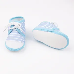 Detailweergave van blauw gestreepte baby-loopschoentjes met zachte zolen en witte veters.