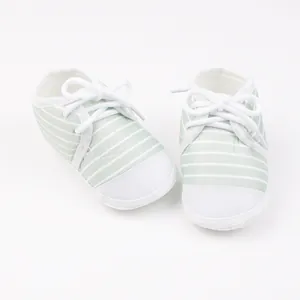 Detailopname van lichtgroen wit gestreepte baby wandelschoenen met zachte witte zolen
