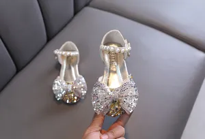 Primer plano de zapatos de princesa plateados con purpurina, lazo y perlas