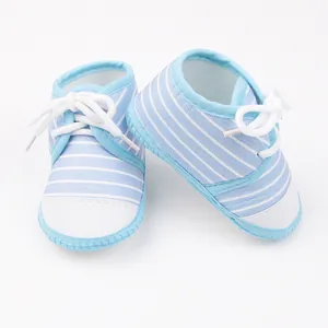 Detailopname van blauw-wit gestreepte babyschoentjes met zachte zool en witte vetersluiting
