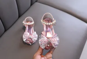 Detalle de zapatos de princesa para niña en rosa brillante con lazo y perlas