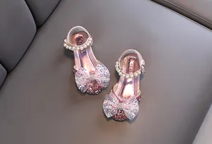 Primer plano de zapatos de princesa rosas para niña con lazo brillante y perlas