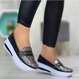 Vista detallada de mocasines negros de mujer con textura de serpiente y plataforma.
