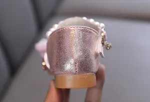 Vista detallada del tacón rosa brillante de un zapato de princesa para niña con perlas