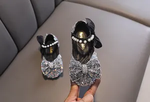 Close-up of girls' silver sequin princess shoes with pearl strap and large bow