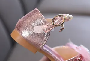 Detalle de zapatos de princesa rosa brillante para niñas con perlas y oro