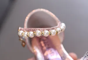 Detalle de correa con perlas y strass en zapatos de princesa rosa brillante