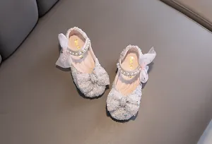 Detailed view of sparkly girls princess shoes with decorative bow and pearl strap
