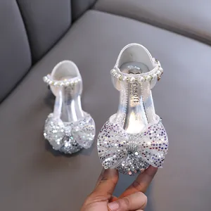 Elegantes zapatos de princesa plateados brillantes para niña con tira de perlas y lazo.