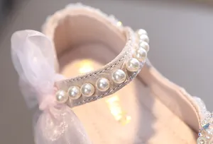 Close-up detail of girls princess shoe with pearl strap and sheer pink ribbon bow.