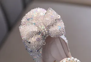 Detail shot of sparkling sequin bow and pearls on elegant girls princess shoes.