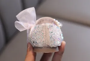 Macro detail of iridescent sequins and sheer bow on pink girl's princess shoe