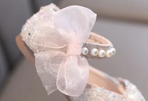 Macro detail of girl's princess shoe with pink mesh bow, pearls, and rhinestones