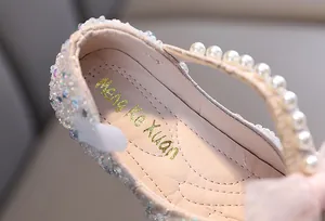 Close-up detail of white pearl strap and silver glitter finish on girl's princess dance shoes