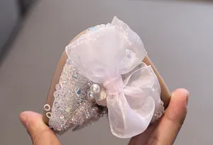 Close-up of elegant girl's princess shoe featuring sparkly sequins and a large sheer bow.