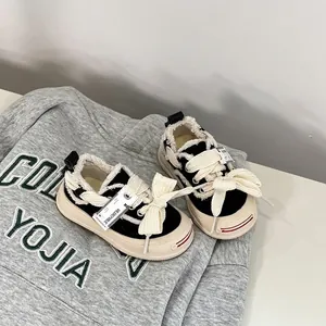 Detailed view of toddler canvas shoes with oversized bow laces and frayed edges