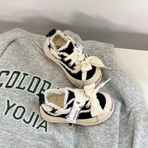 Detailed close-up of black and white baby canvas walking shoes with bow knot laces