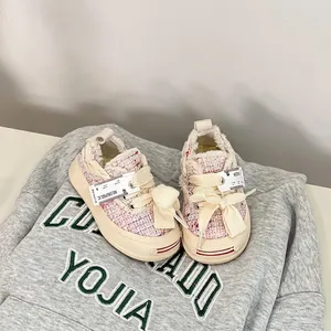 Detail view of pink tweed baby walker shoes featuring decorative large cream cotton bow laces
