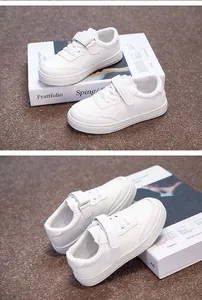 Detailed close-up of minimalist white children's sneakers with velcro straps for school use
