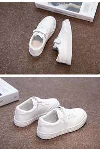 Macro view of solid white children's sneakers featuring adjustable velcro strap design.
