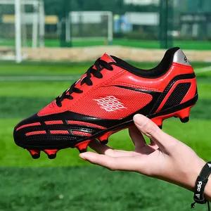 Scarpe da calcio professionali rosse e nere con tacchetti antiscivolo per ragazzi.