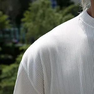 Close-up detail of white plissé pleated fabric texture on a men's summer casual top.
