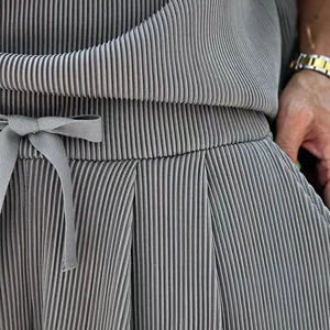 Close-up of grey pleated fabric texture on men's casual shorts set with drawstring