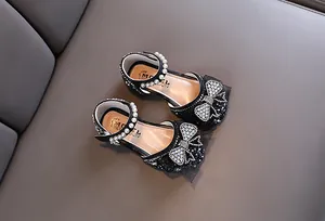 Detail van zwarte prinsessensandalen voor meisjes met strass-vlinderstrik en parels