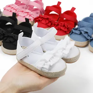 Primer plano de sandalias blancas con volantes para bebé en mano, opciones coloridas