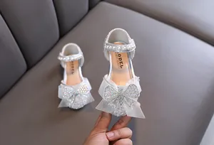 Detailopname van sprankelende zilveren prinsessenschoenen met mesh strik en parels.