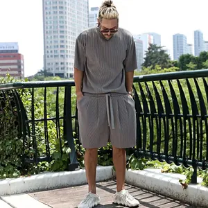 Detail view of a men's loose-fit grey vertical pleated short sleeve and shorts set outdoors