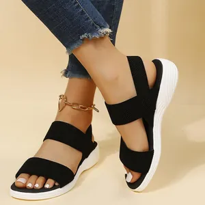 Detalle de sandalias de cuña tejidas en negro con correas elásticas para la playa en verano